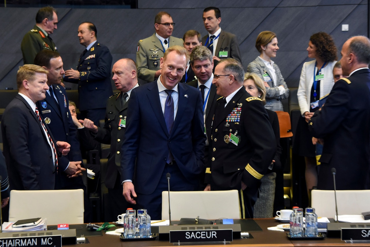 Acting Defense Secretary Patrick M. Shanahan talks to Army Gen. Curtis M. Scaparrotti with people in the background.