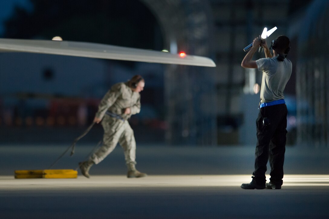 U.S. Air Force Senior Airman Jacob Milbrath, 1st Aircraft Maintenance Squadron crew chief, prepares to launch an F-22 Raptor as his fellow Airman removes the chocks at Joint Base Langley-Eustis, Va., July 11, 2017.