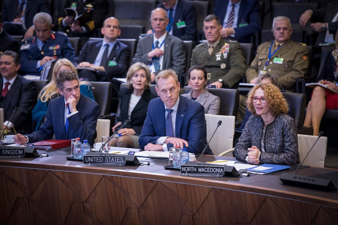 Acting Defense Secretary Patrick M. Shanahan sits in between two people.