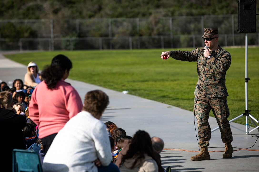 GySgt. Mark Daniels, a military working dog (MWD) handler at Marine Corps Air Station Miramar, speaks to students during a MWD demonstration at Dingeman Elementary School, San Diego, Calif., Feb. 12. MCAS Miramar conducted this demonstration to teach students about the MWD handler military occupational specialty as well as foster cohesion with the surrounding community. (U.S. Marine Corps photo by Sgt. Jake McClung)