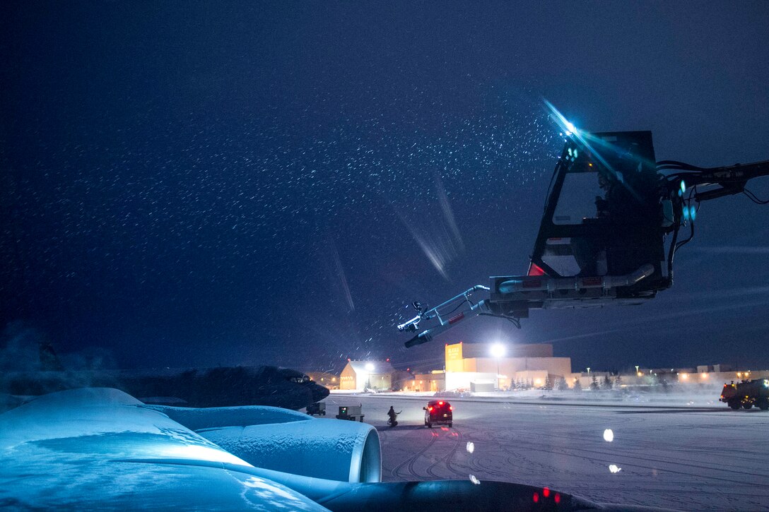 A de-icing machine works on a flightline at night.