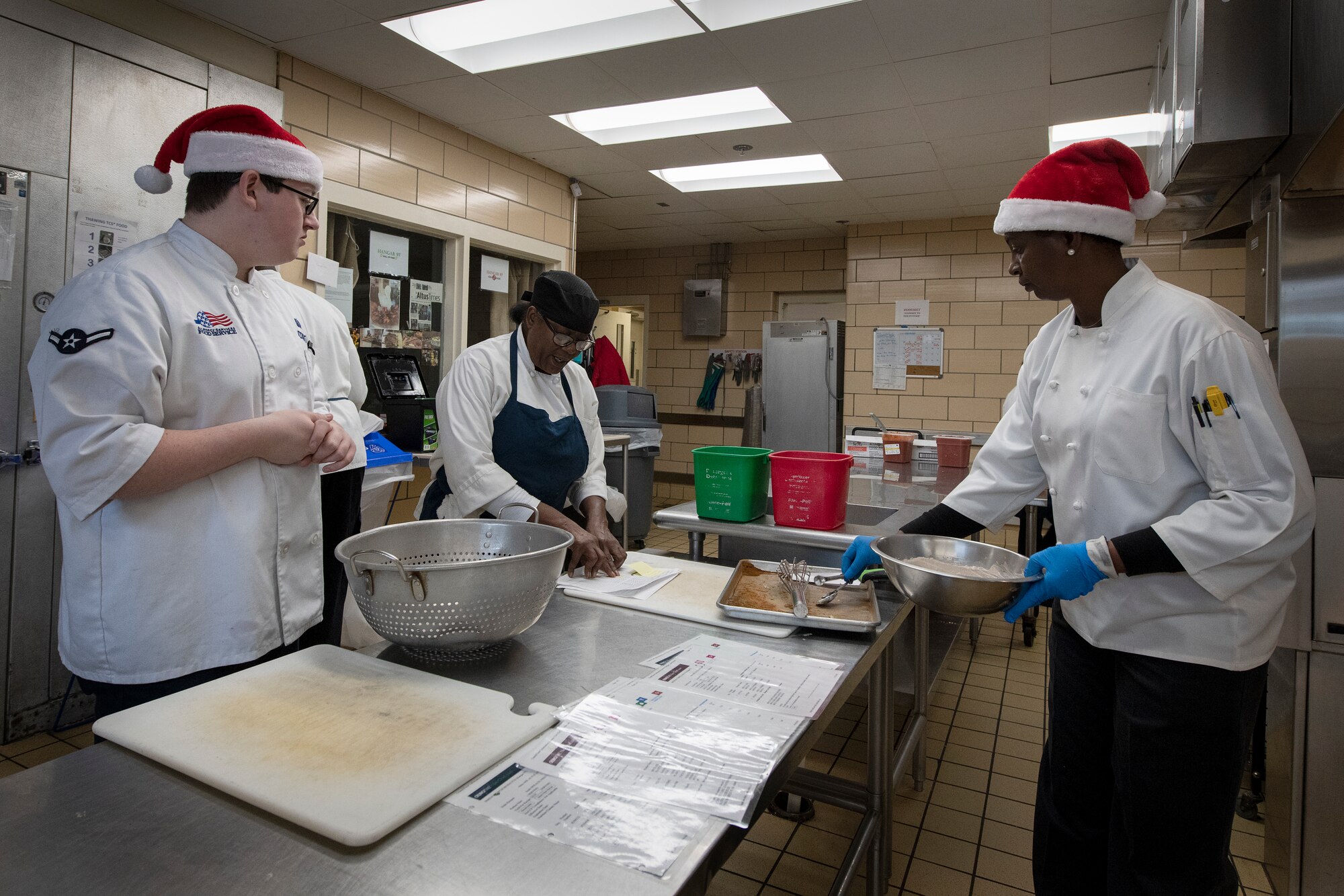 Airman Bryce Doherty, a food services specialist assigned to the 97th Force Support Squadron, with Starr Fanner and Paula Seamster, cooks from the Hangar. 97 Dining Facility, prepare food Dec. 19, 2018 at Altus Air Force Base, Okla