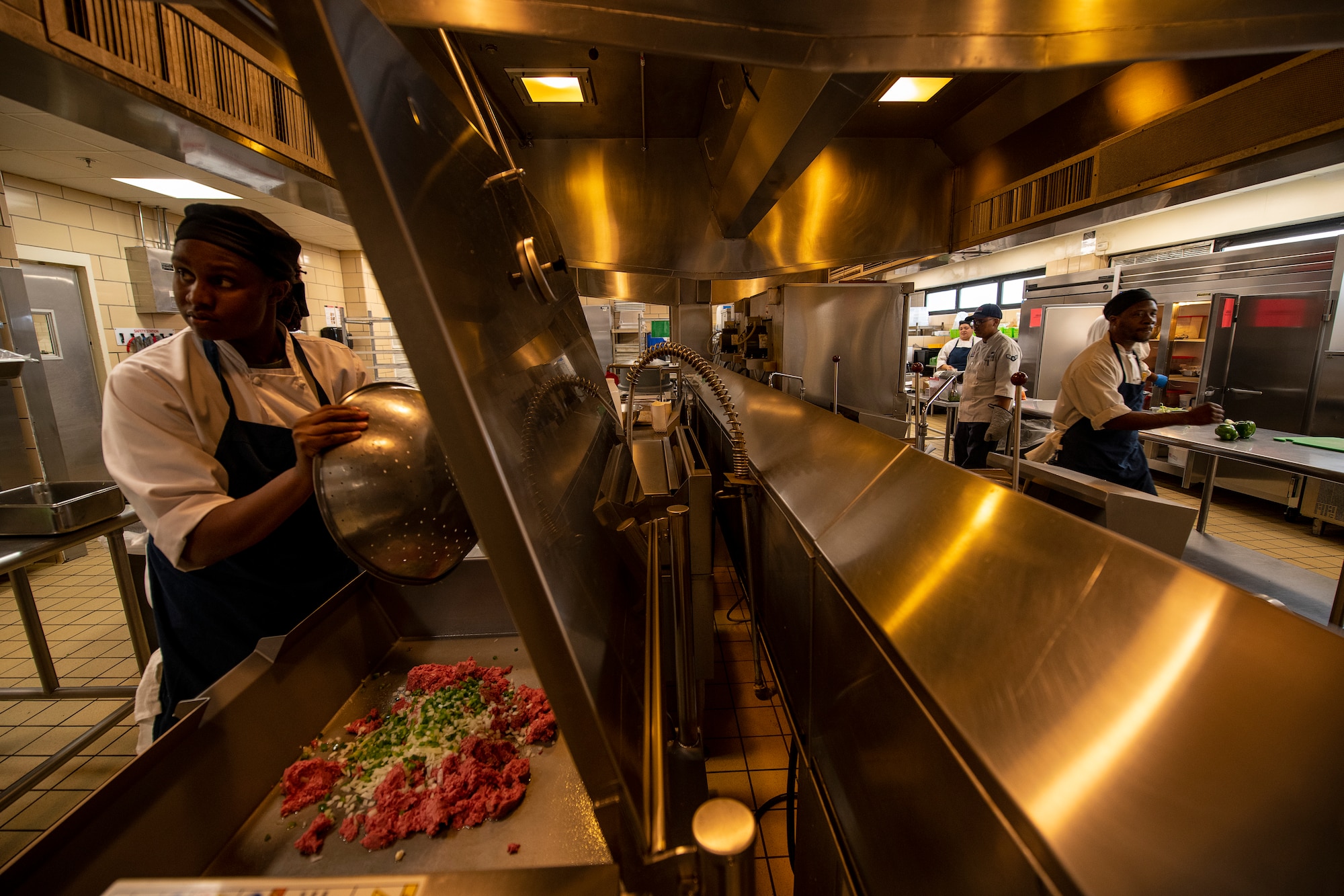 Dede Coats, a cook from the Hangar 97 Dining Facility adds ingredients to an industrial grill, Jan. 10, 2019 at Altus Air Force Base, Okla.