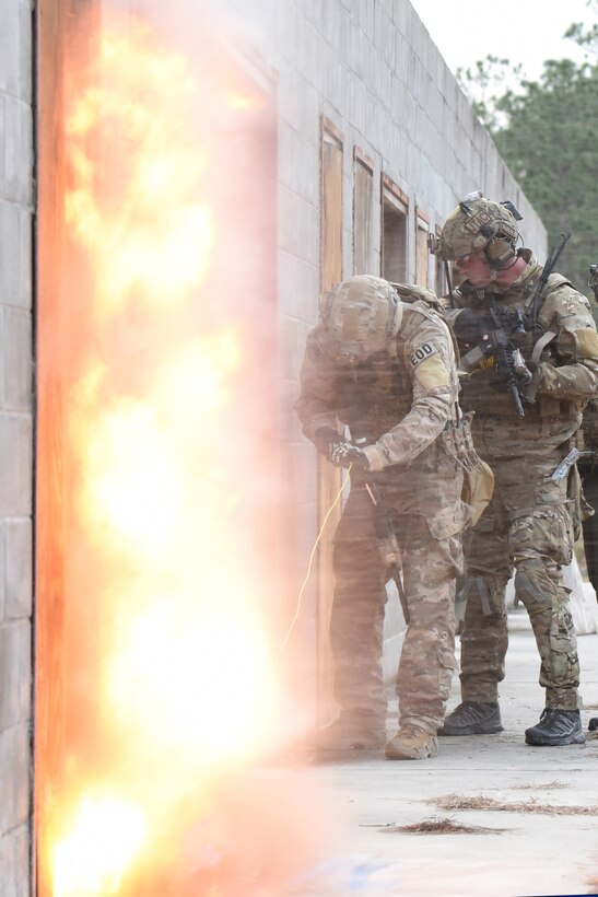 Staff Sgt. Ethan Johnson, an explosives ordnance technician in the 119th Wing, detonates an explosive tool which had been placed on a door as Senior Airman Tyler Herlihy, a tactical air control party (TACP) Airman in the 169th Air Support Operations Squadron (ASOS), provides support as they prepare to breach a door while conducting training during Exercise Southern Strike 19 at Camp Shelby Joint Forces Training Center near Hattiesburg, Miss., Jan. 18, 2019.