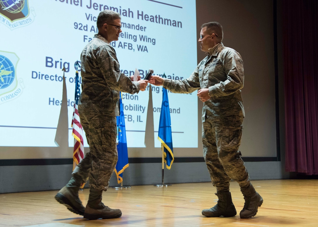 U.S. Air Force Brig. Gen. Steven Bleymaier, Air Mobility Command Logistics, Engineering and Force Protection director, is handed a microphone by Col. J. Scot Heathman, 92nd Air Refueling Wing vice commander, before addressing attendees at the Mobility Guardian 2019 International Planning Conference held at Fairchild Air Force Base, Washington, Feb. 5, 2019.