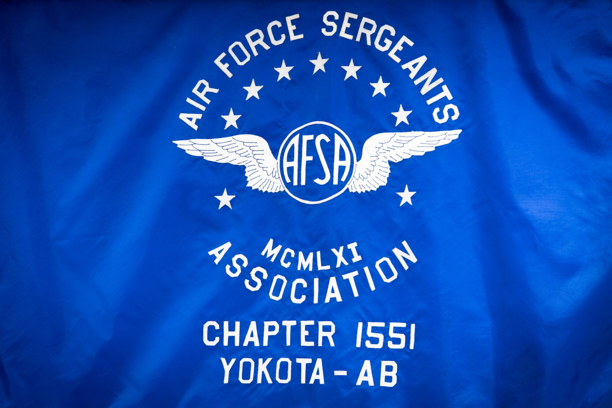 The Air Force Sergeants Association Chapter 1551 Yokota Air Base flag hangs on a wall during the second annual Mentoring Up event, Feb. 7, 2018, at Yokota Air Base, Japan. Mentoring up is sponsored by the AFSA and provides a unique opportunity for ambitious Airmen who are leading their tier to present pressing matters and innovative ideas to senior enlisted leaders. (U.S. Air Force photo by Senior Airman Donald Hudson)