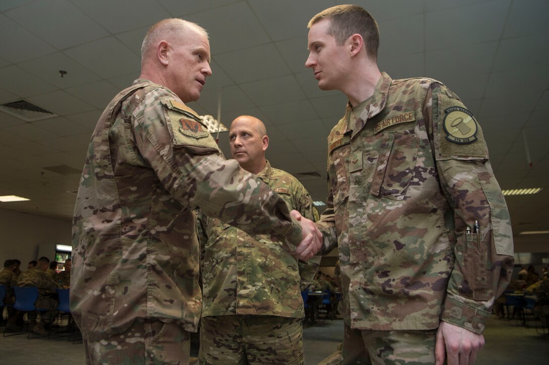 Chief Master Sgt. Frank Batten, Air Combat Command command chief, coins Senior Airman Joshua Kampfe, 379th Expeditionary Communications Squadron, during an ACC leadership visit Feb. 11, 2019, at Al Udeid Air Base, Qatar.