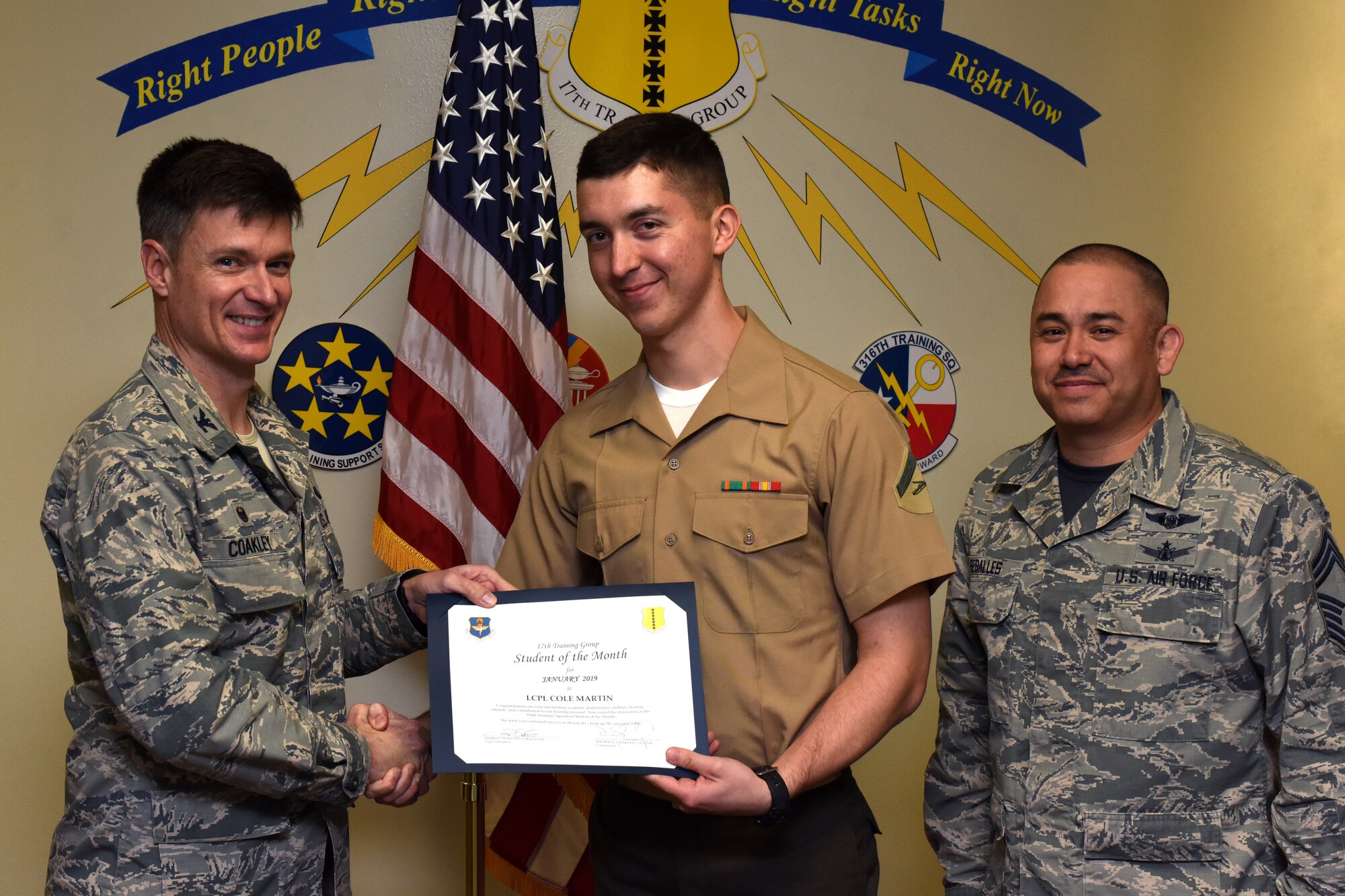 U.S. Air Force Col. Thomas Coakley, 17th Training Group commander, presents the 316th Training Squadron Student of the Month award to Lance Cpl. Cole Martin, 316th TRS student, at the Brandenburg Hall on Goodfellow Air Force Base, Texas, Feb. 8, 2019. The 316th TRS’s mission is to conduct U.S. Air Force, U.S. Army, U.S. Marine Corps, U.S. Navy and U.S. Coast Guard cryptologic, human intelligence and military training. (U.S. Air Force photo by Airman 1st Class Zachary Chapman/Released)