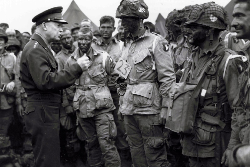 Gen. Eisenhower talks with paratroopers on an airfield in England.