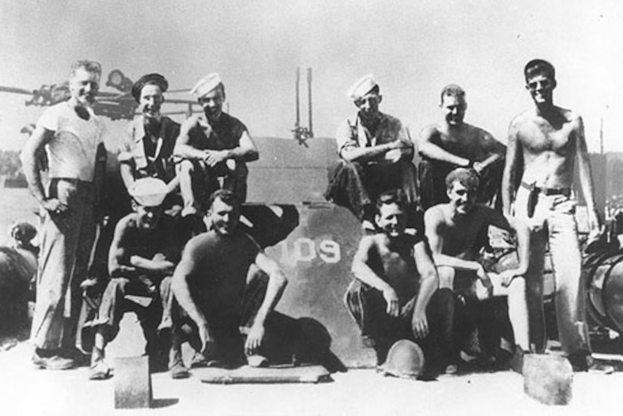 Several sailors pose for a photo on a motor torpedo boat.