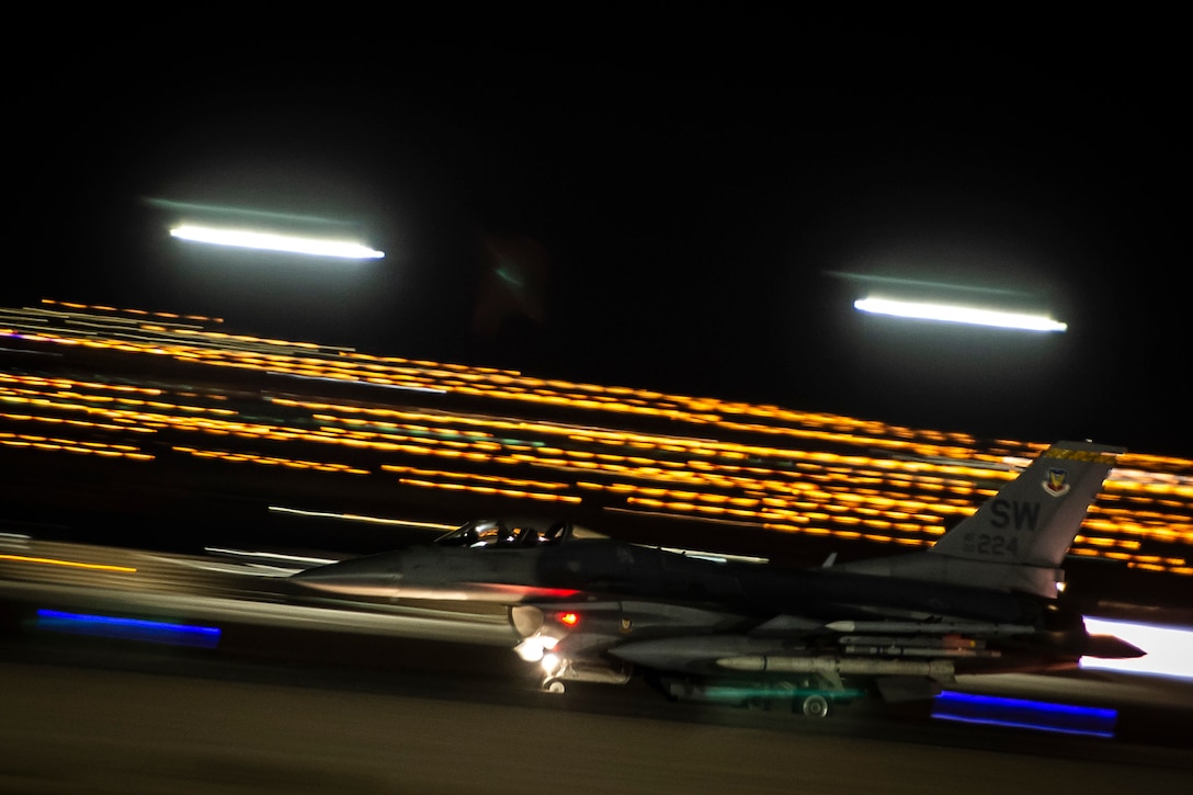 Bright stripes of yellow light illuminate a dark sky as a jet takes off.