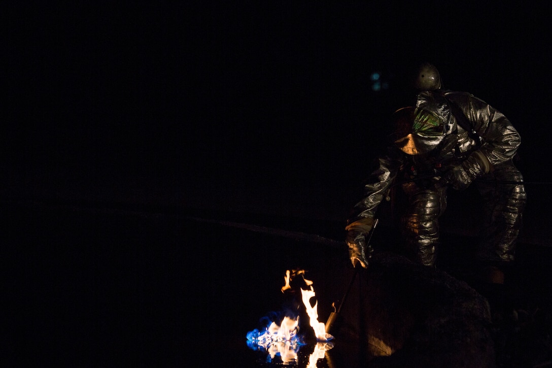 U.S. Marines with Aircraft Rescue and Firefighting (ARFF) ignite a fuel fire in a training pit Jan. 24, 2019 during live-burn training on Marine Corps Air Station Futenma, Okinawa, Japan. The training is held monthly to provide ARFF Marines with training scenarios to enhance their readiness to respond to any potential hazards or emergencies on the flight line. ARFF Marines entered the training area and used various hand lines, also known as a fire hose, to control and extinguish the fire. (U.S. Marine Corps photo by Lance Cpl. Nicole Rogge)