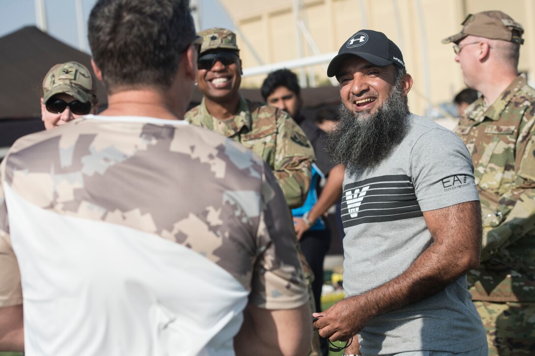Brig. Gen. (Pilot) Saif Rashid Al-Khayarin, Qatar Emiri Air Force intelligence director (center right), talks with U.S. Air Force Brig. Gen Jason Armagost, 379th Air Expeditionary Wing commander (left), during Qatari National Sports Day Feb. 12, 2019, at Al Udeid Air Base, Qatar. U.S. and Qatar military forces were able to compete in team events including basketball, volleyball and soccer, as well as individual events such as swimming and ping pong throughout the morning. Qatari National Sports Day provided servicemembers from both nations an opportunity to strengthen military relations through friendly competition. (U.S. Air Force photo by Tech. Sgt. Christopher Hubenthal)