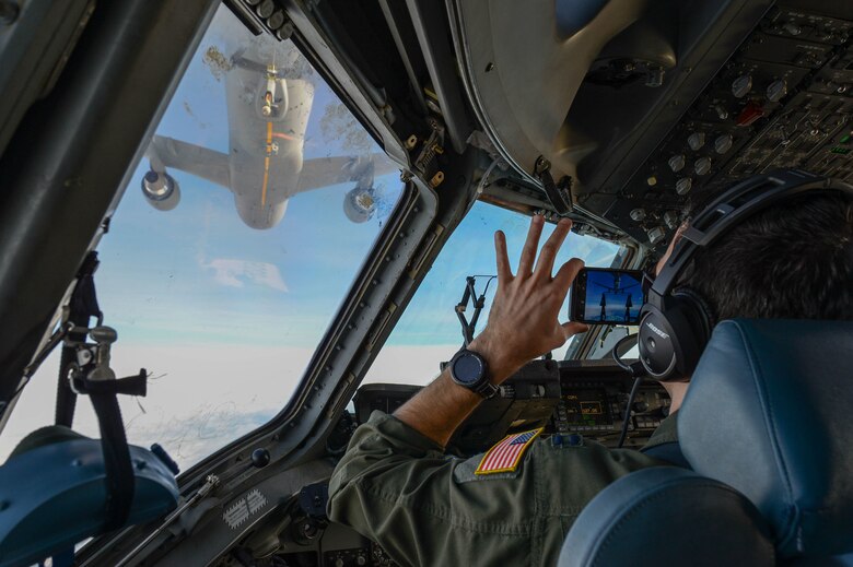 A pilot documents training while another pilot prepares to refuel from a KC-46 Pegasus