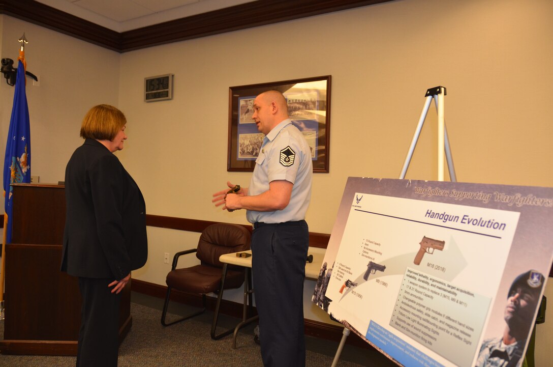 Master Sgt. Jason Wilson, manager of the Air Force Ground Munitions Program at the Air Force Security Forces Center, explains the benefits of the new Air Force M18 modular handgun system to Lorna Estep, AFIMSC executive director, on Feb. 4.