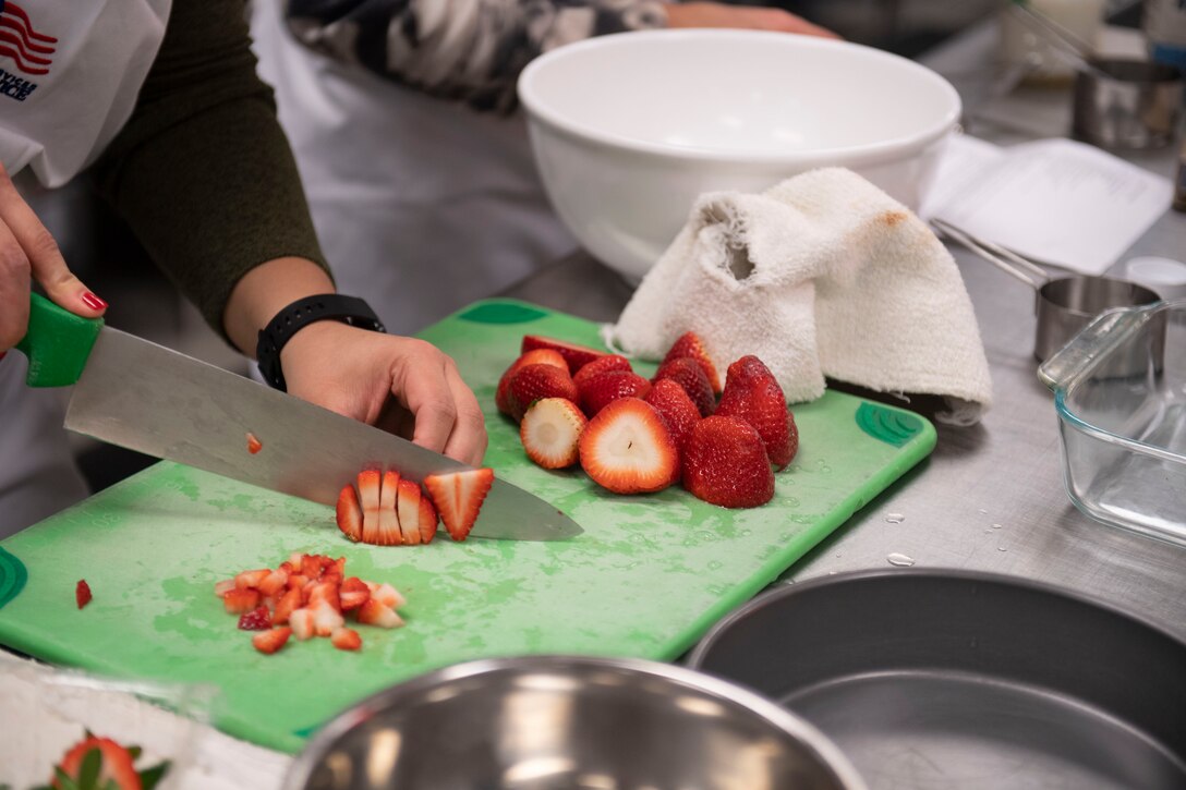 A contestant cuts strawberries during the first Cupid Cake Wars, Feb. 13, 2019, at Moody Air Force Base, Ga. The event consisted of contestants working together in teams to create, bake and design their most inspired Valentine’s Day-themed cakes. (U.S. Air Force Photo by Airman 1st Class Joseph P. Leveille)