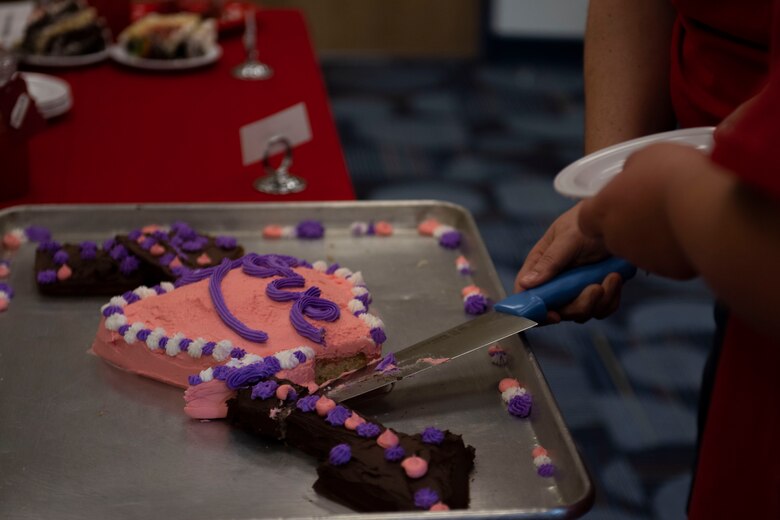 Heather Brooks, left, and her daughter Laila, contestants, serve cake to the judges. The event consisted of contestants working together in teams to create, bake and design their most inspired Valentine’s Day-themed cakes. (U.S. Air Force Photo by Airman 1st Class Joseph P. Leveille)