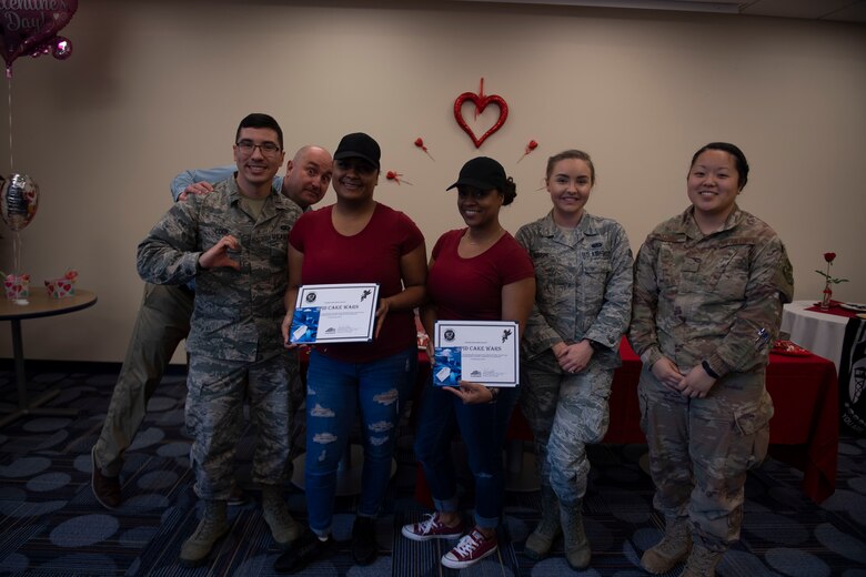 Team Sister Sister along with the judges pose for a photo during the first Cupid Cake Wars, Feb. 13, 2019, at Moody Air Force Base, Ga. After being evaluated, team Sister Sister’s cake won first place in the competition. (U.S. Air Force Photo by Airman 1st Class Joseph P. Leveille)