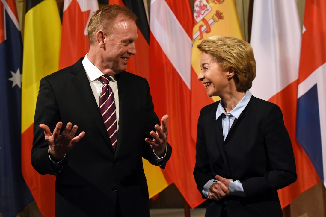 Two defense leaders stand and talk.