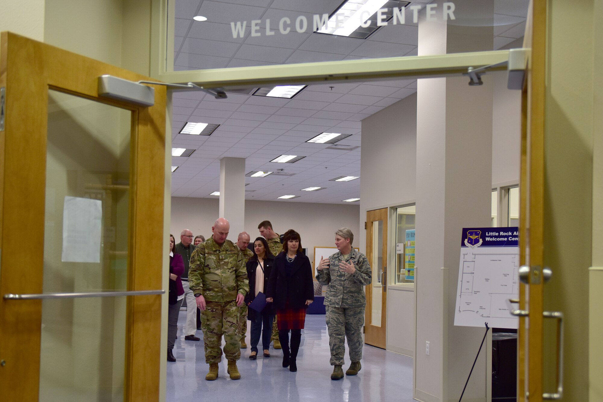 A woman in the Airman Battle Uniform shows people a welcome center.