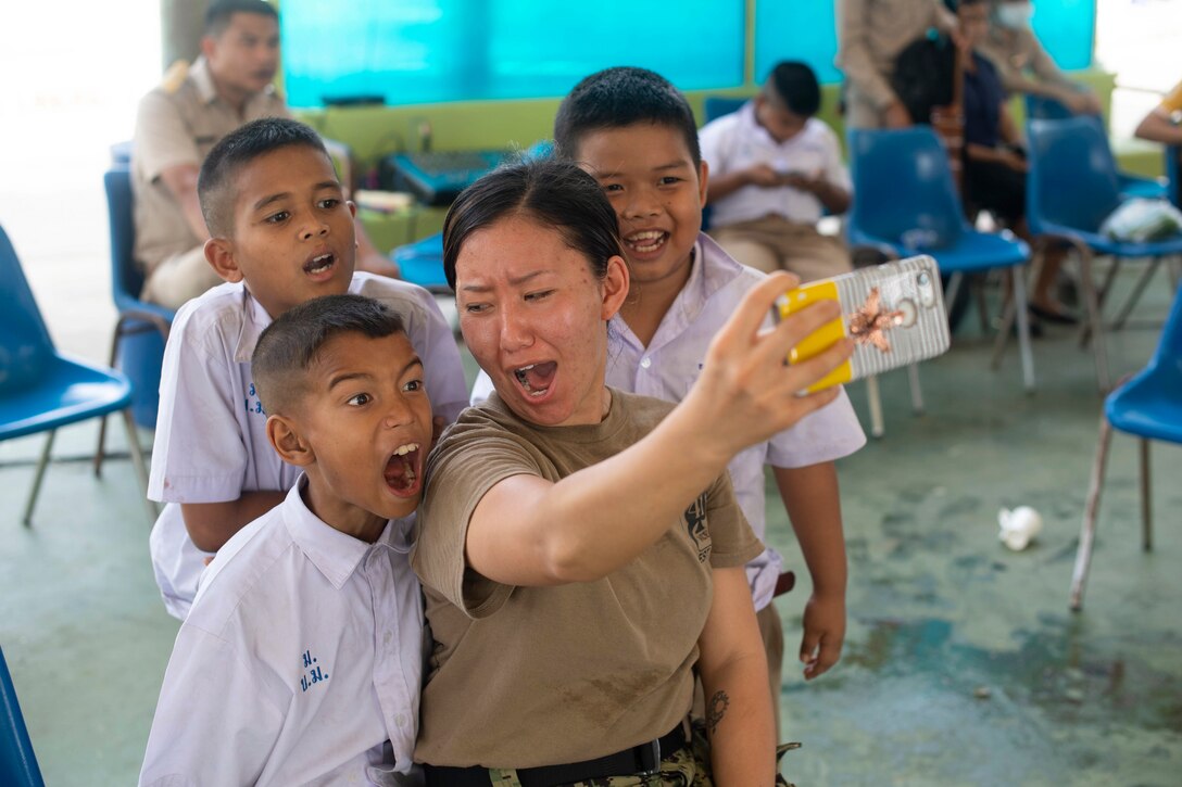 A sailor takes a selfie with three children.