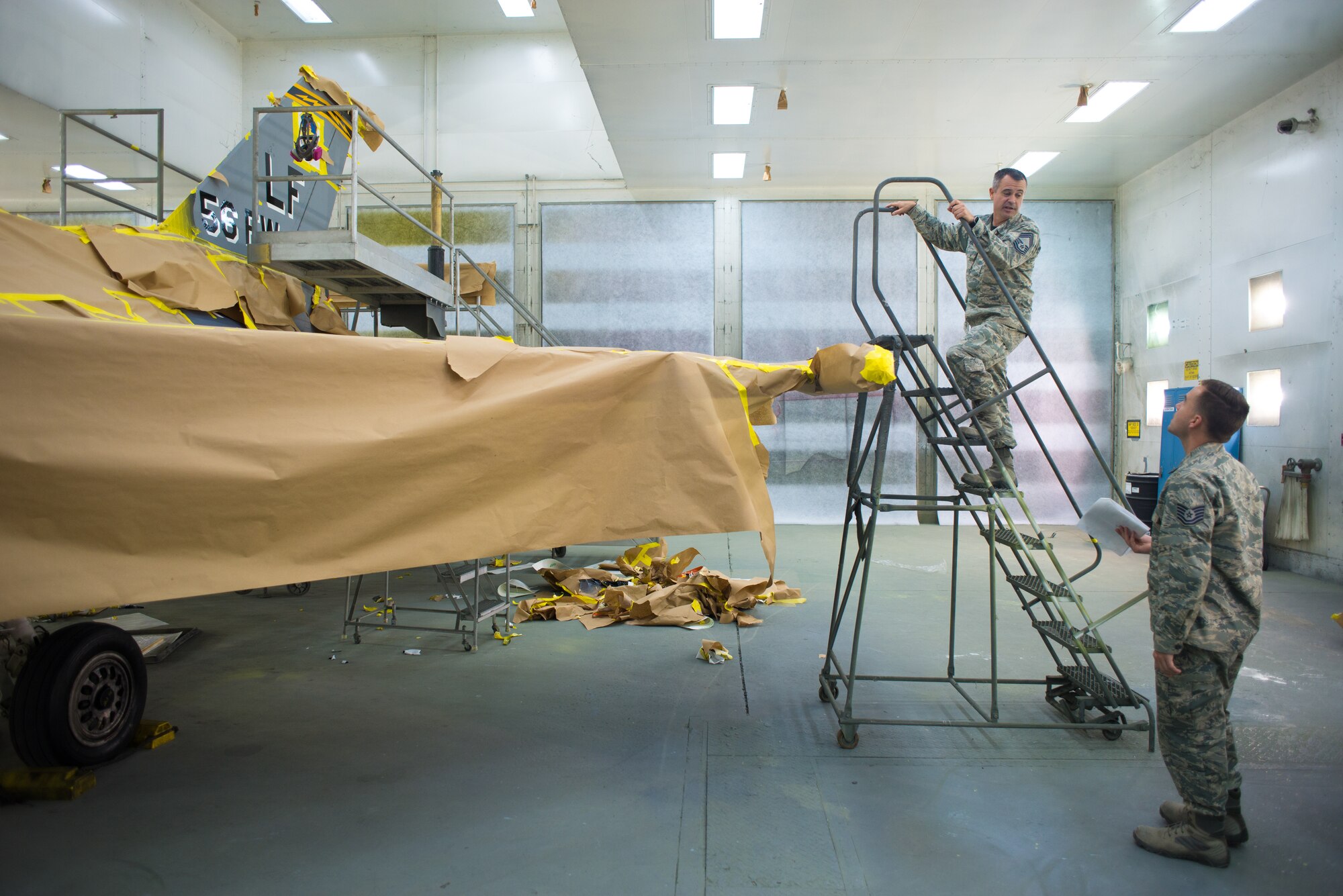 Chief Master Sgt. Jonathan Veal, 310th Aircraft Maintenance Unit superintendent, and Tech. Sgt. Jason Stachowski, 56th Equipment Maintenace Squadron corrosion control non-commissioned officer in charge, examine the repainting progress of an F-16 Fighting Falcon at Luke Air Force Base, Ariz. Veal and Stachowski were key players in the approval process, design and implementation of the vintage paint scheme. (U.S. Air Force photo by Senior Airman Caleb Worpel)