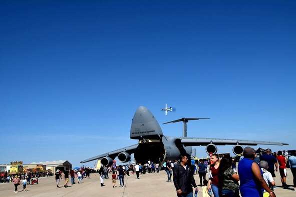 Spectators walk to a 433rd Airlift Wing’s C-5M Super Galaxy from Joint Base San Antonio-Lackland, Texas while an A-10C Thunderbolt II performs during the Washington’s Birthday Celebration Association Stars and Stripes Air Show Spectacular at the Laredo International Airport in Laredo, Texas Feb. 17, 2019.