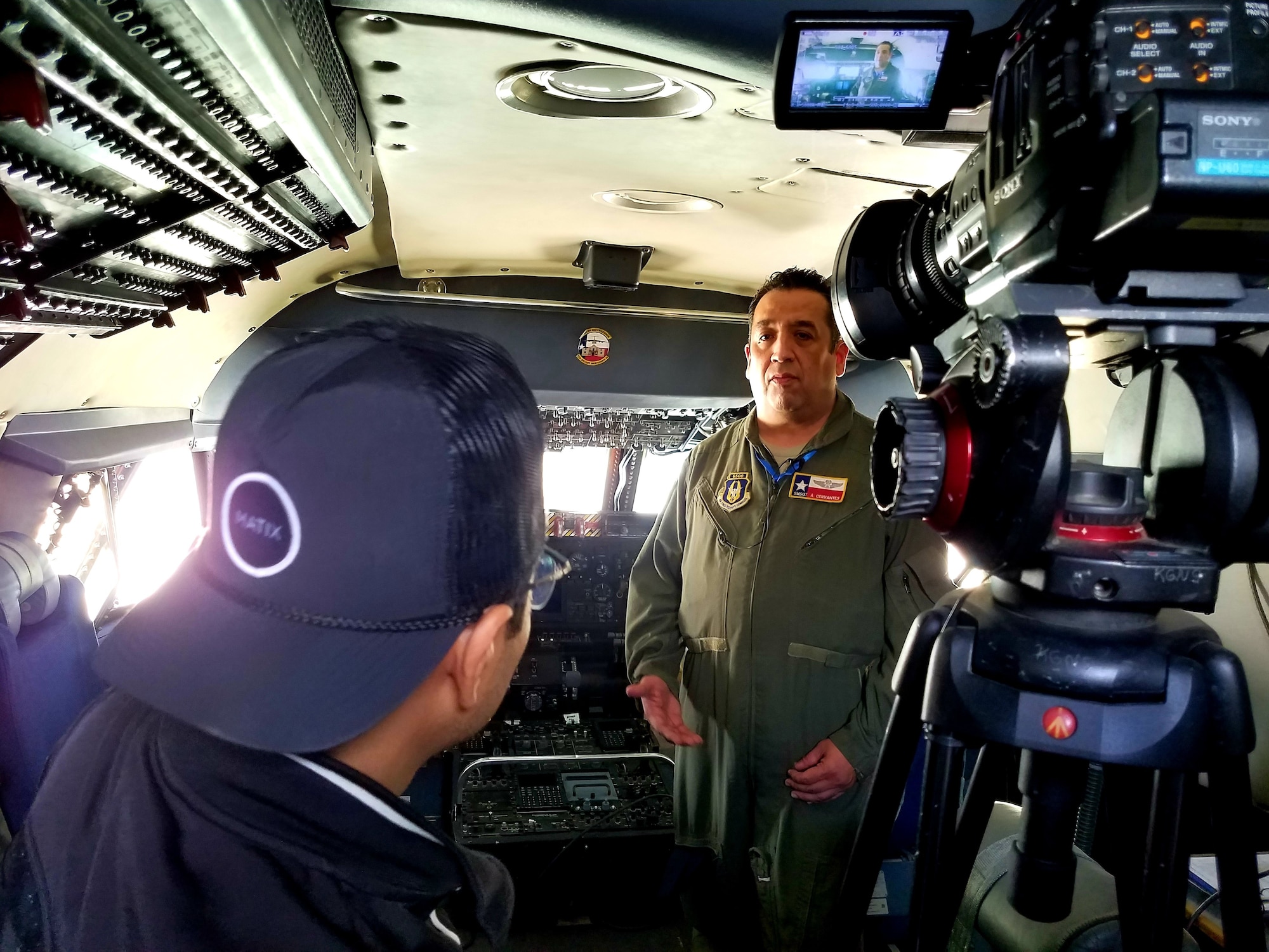 Senior Master Sgt. Alfonso Cervantes, 68th Airlift Squadron loadmaster, speaks with a local television station crew in both English and Spanish while in the cockpit of the 433rd Airlift Wing’s C-5M Super Galaxy from Joint Base San Antonio-Lackland, Texas at the Laredo International Airport in Laredo, Texas Feb. 17, 2019.