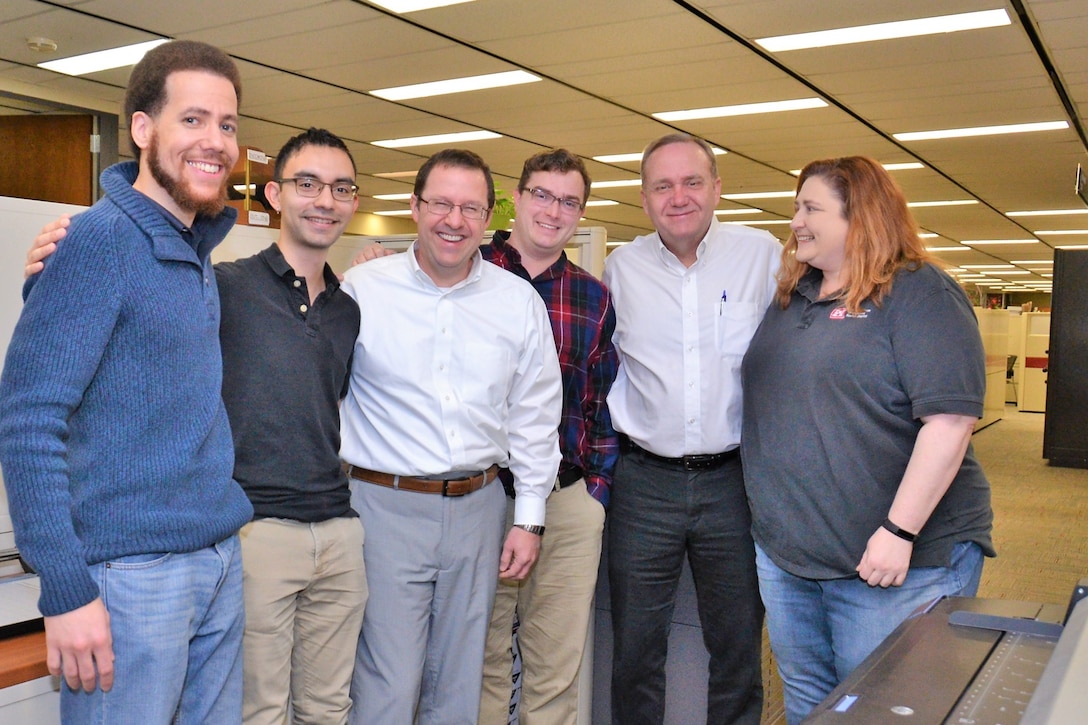 Six people standing around in an office