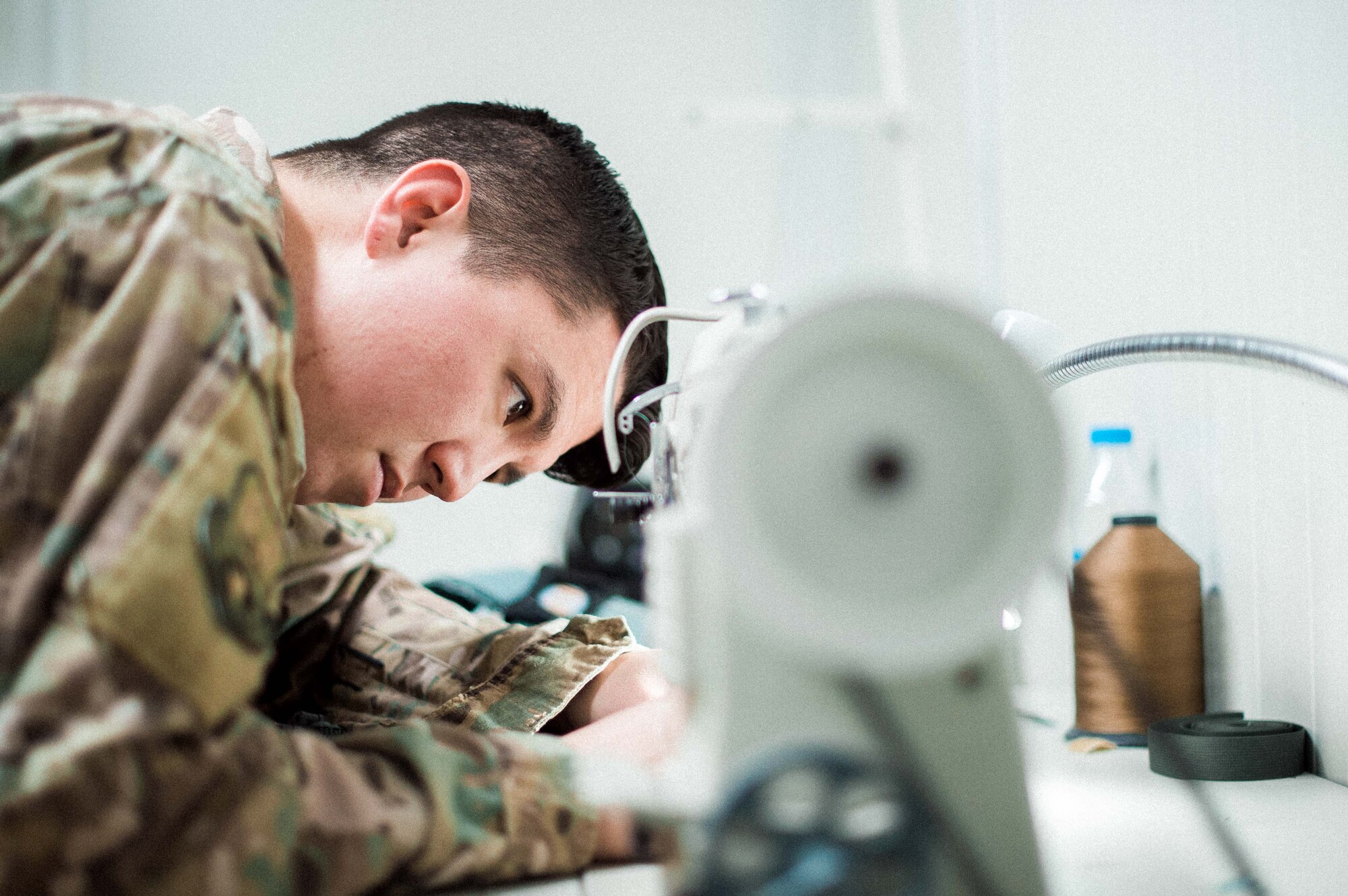 U.S. Air Force Staff Sgt. Andrew Yabumoto, 493rd EFS aircrew flight equipment apprentice, sews a harness February 14, 2019 in Southwest Asia. The AFE shop works around the clock to ensure aircrew members’ daily equipment, which includes G-suits, night vision goggles, harnesses, helmets and oxygen masks are ready to go at a moment’s notice. (U.S. Air Force photo by Staff Sgt. Delano)