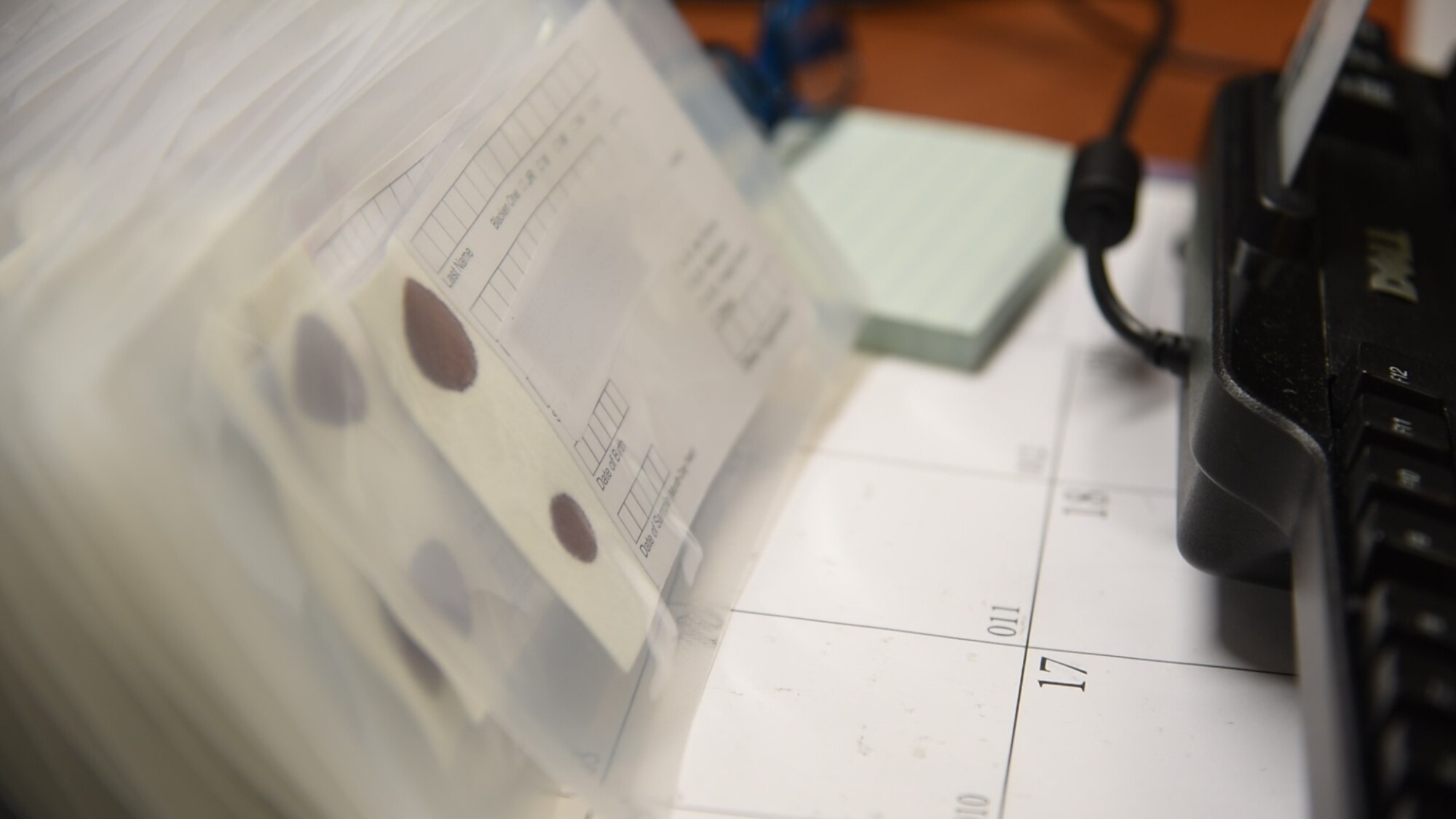 A stack of blood stain cards rest on the desk of an Armed Forces Repository of Specimen Samples for the Identification of Remains (AFRSSIR) technician’s desk Jan. 30, 2019, at Dover Air Force Base, Del. AFRSSIR maintains approximately 7.9 million blood stain cards, preserving the DNA of U.S. service members, primarily to ensure fallen service members are returned to their families. (U.S. Air Force Photo by Senior Airman Dedan D. Dials) (This photo has been altered for security purposes by blurring out personally identifiable information.)