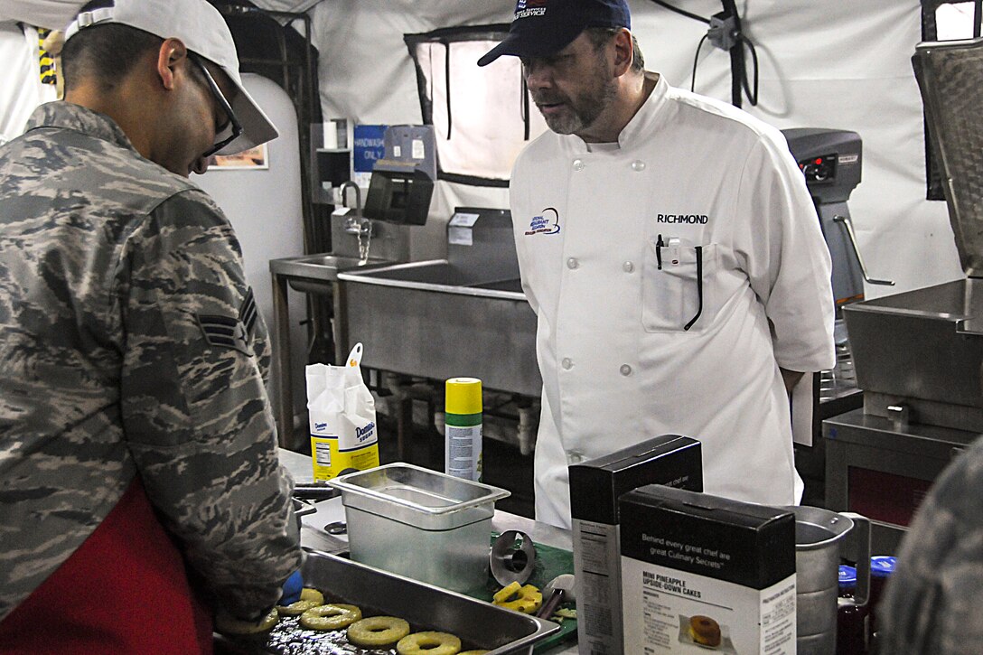 A judge watches meal preparation during this year's Hennessy competition held at the Force Support Silver Flag training facility on Dobbins Air Reserve Base Feb. 9-12. Each year a trophy is awarded to teams representing the best food service programs in the Air Force and is based on the entire scope of an installation's food service program. (U.S. Air Force photo/Senior Airman Justin Clayvon)