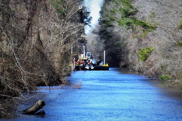 a small boat on a creek with threes on either side of the water