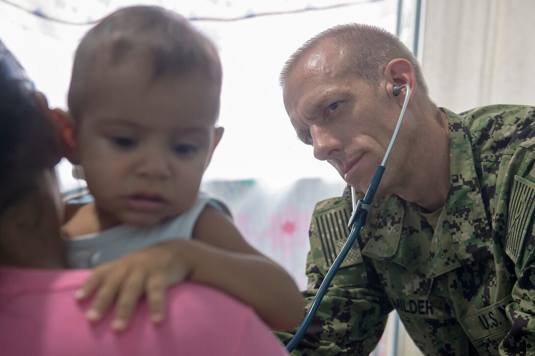 Cmdr. Edmund Milder examines a young patient at the Benjamin Silva-Calama clinic in Calama, Brazil, Feb. 14.