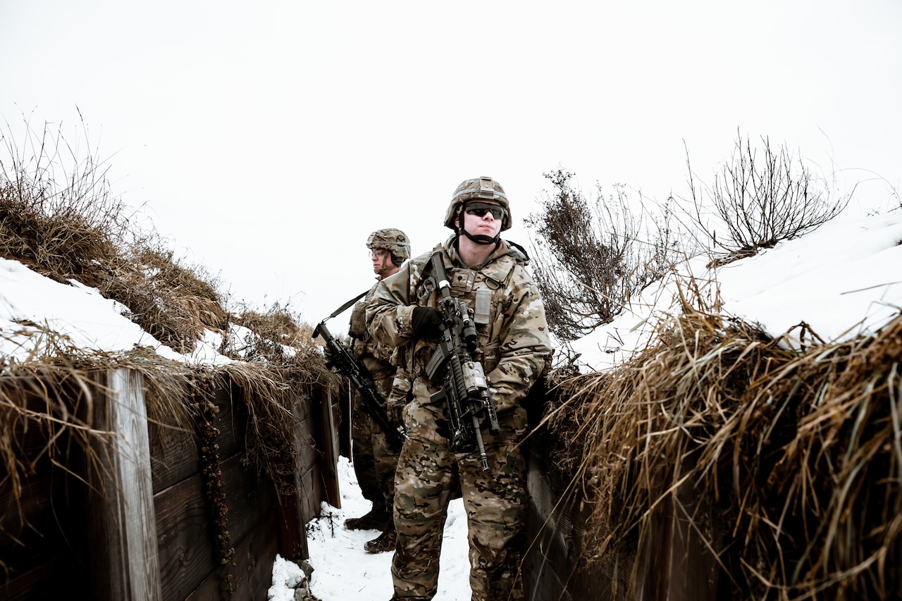 Soldiers walk through trench