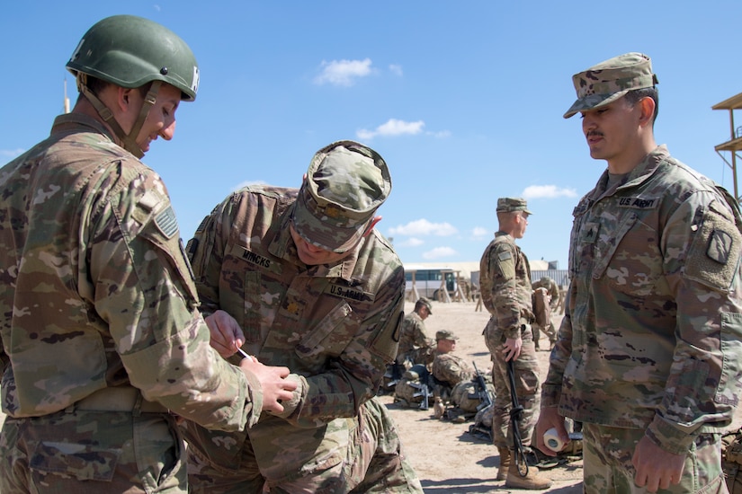 Army Maj. Jeff Mincks, a physician assistant assigned to the 2nd Combined Arms Battalion, 137th Infantry Regiment, Kansas Army National Guard, out of Kansas City, Missouri, applies medical care to a student during day seven of Air Assault School’s Class 301-19 on Feb. 12, 2019, at Camp Buehring, Kuwait. Sergeant Michael Pretorius, a combat medic, Kansas Army National Guard, stands ready to provide more bandages.