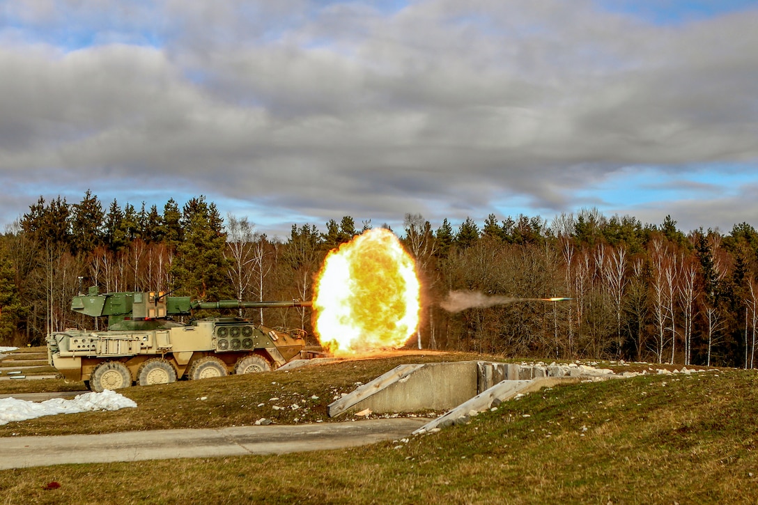 A projectile and a fireball shoot out from a military vehicle's gun.