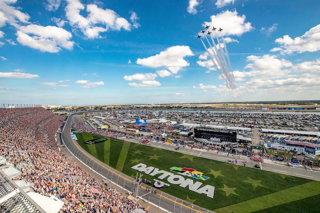 Jets fly in formation over a crowd at the Daytona International Speedway.
