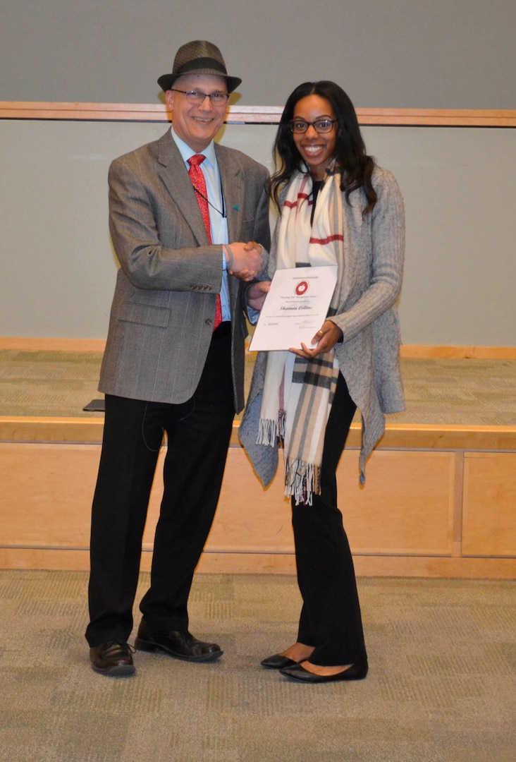 Defense Logistics Agency Troop Support Subsistence supply chain Deputy Director Rich Faso presents the Subsistence Shooting Star Award to Shannon Collins during a town hall in Philadelphia, Dec.12, 2018. Collins, a contract specialist in the Supplier Operations directorate, received the award for her efforts to make use of unmanned air systems, or drones, to deliver food and water to areas not accessible by normal modes of transportation.