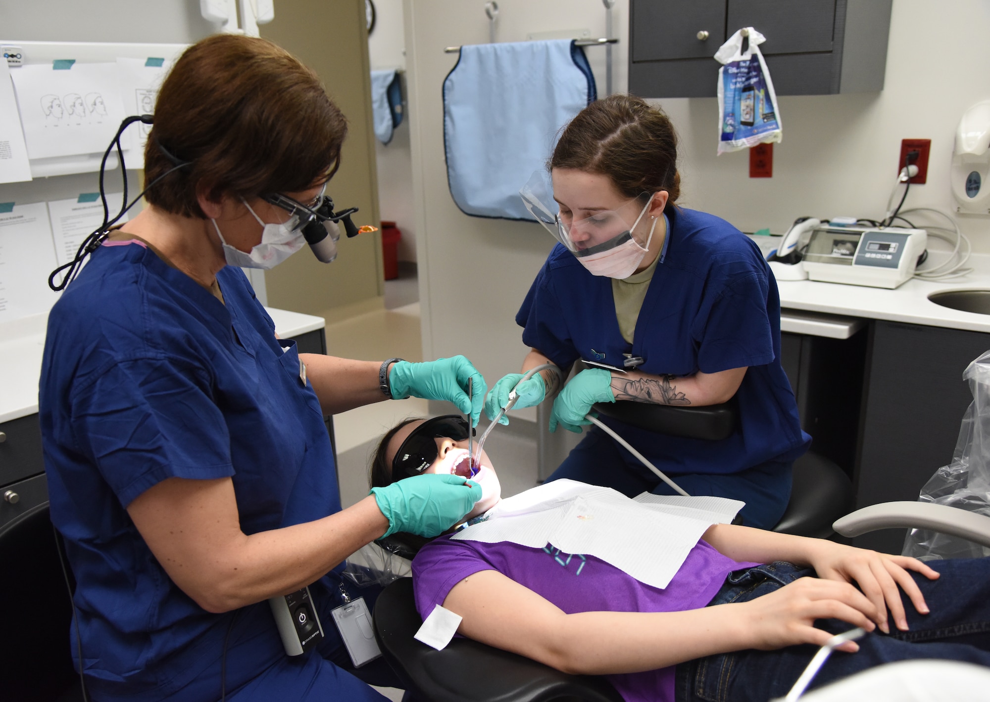 U.S. Air Force Maj. Iwona Rusiecka, 81st Dental Squadron resident, and Airman 1st Class Audrey Mitstifer, 81st DS dental assistant, clean the teeth of Andrea Linstrom, daughter of Master Sgt. Kenneth Linstrom, 336th Training Squadron flight chief, during the 9th Annual Give Kids a Smile Day at the dental clinic inside the Keesler Medical Center at Keesler Air Force Base, Mississippi, Feb. 15, 2019. The event was held in recognition of National Children's Dental Health Month and included free dental exams, radiographs and cleanings for children age two and older. (U.S. Air Force photo by Kemberly Groue)