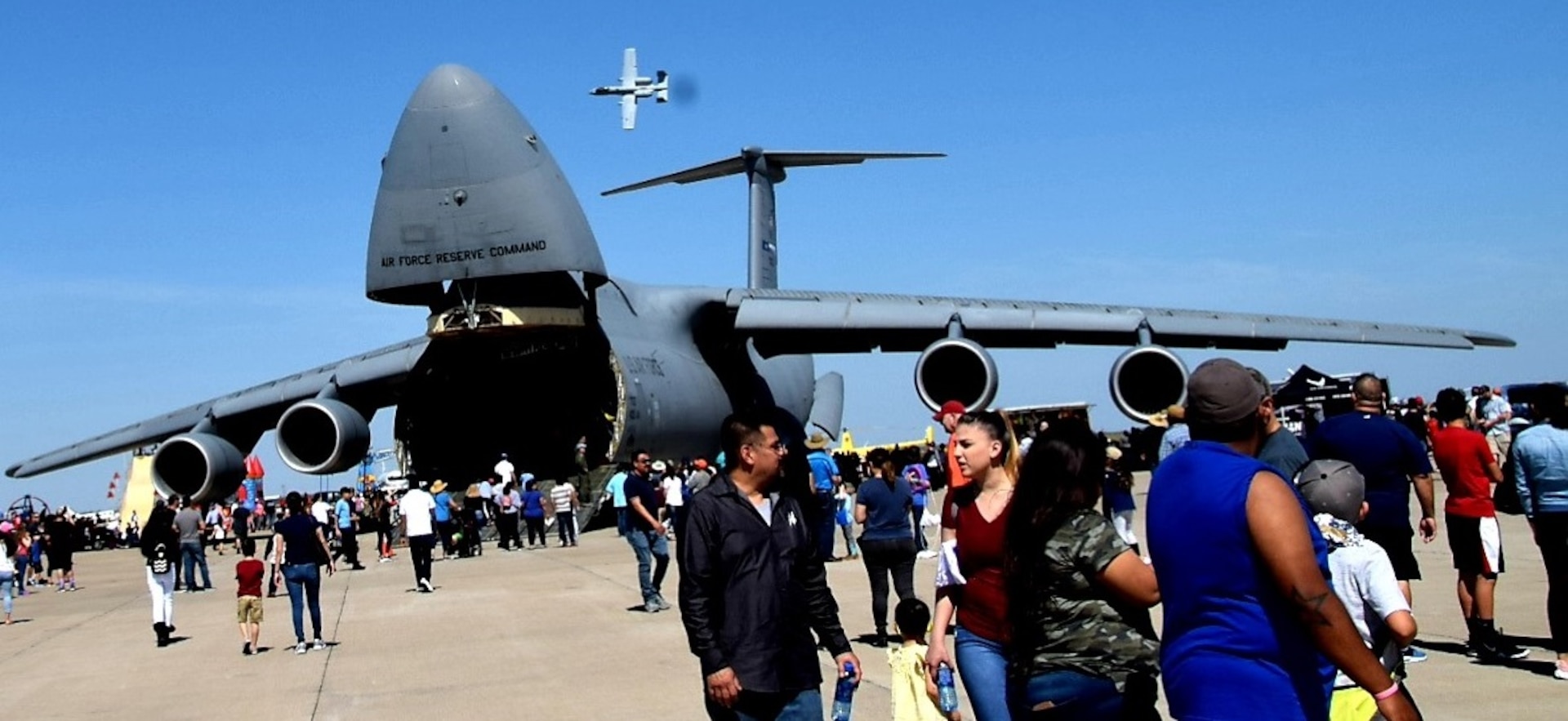 Spectators walk to a 433rd Airlift Wing’s C-5M Super Galaxy from Joint Base San Antonio-Lackland while an A-10C Thunderbolt II performs during the Washington’s Birthday Celebration Association Stars and Stripes Air Show Spectacular at the Laredo International Airport in Laredo, Texas Feb. 17. The A-10 belongs to the A-10C Thunderbolt II Demonstration Team from Davis-Monthan Air Force Base, Arizona.