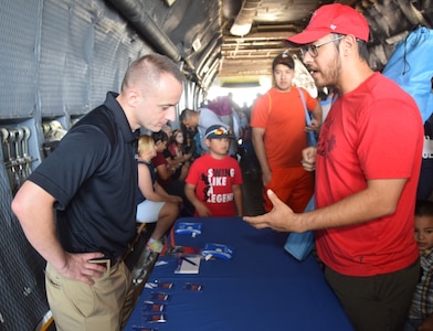 Air Force Reserve Recruiter Tech. Sgt. Joshua Marcum (left) from Corpus Christi talks to an air show attendee at the Washington’s Birthday Celebration Association Stars and Stripes Air Show Spectacular at the Laredo International Airport in Laredo, Texas, Feb. 17. Due to high winds at the airport, the recruiter moved his table to the inside of the Alamo Wing’s C-5M Super Galaxy.