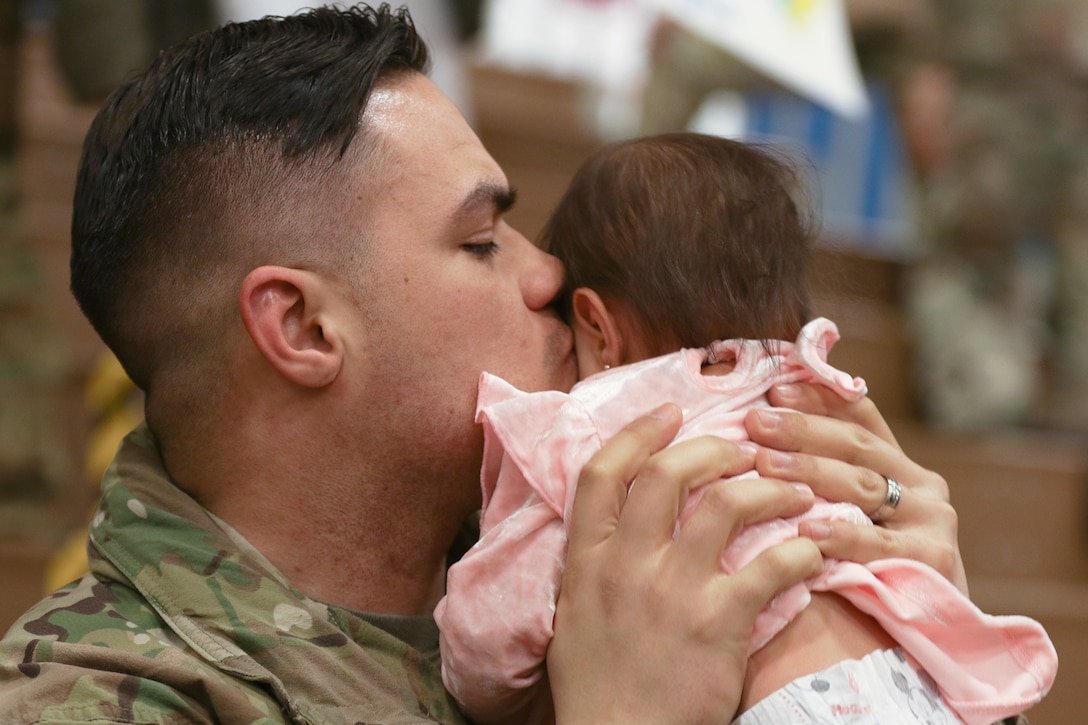 A service member hugs a child.