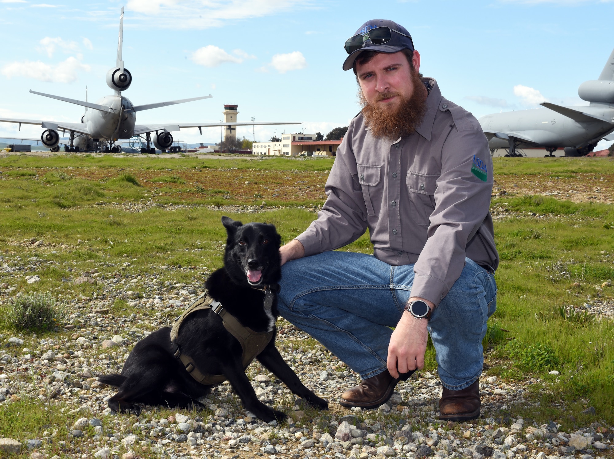 Otto, the safety dog, and his handler, Matt Stevens, U.S. Department of Agriculture airport biologist, pose for a photo Feb. 20, 2019, at Travis Air Force Base, Calif. Matt rescued and trained Otto so they could work together to prevent bird and aircraft strikes. (U.S. Air Force photo by Airman 1st Class Christian Conrad)