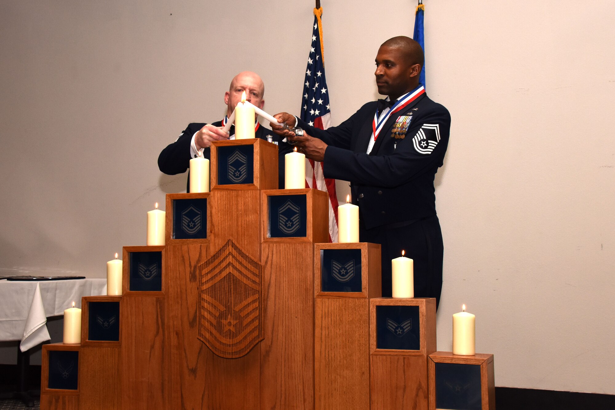 U.S. Air Force Senior Master Sgt. Jeffrey Henson, 316th Training Squadron superintendent, and Senior Master Sgt. Jerome Wright, 315th Training Squadron operations superintendent, light the final candle on the pyramid of all enlisted ranks in the Air Force during the Chief Master Sgt. Induction Ceremony at the Event Center on Goodfellow Air Force Base, Texas, Feb. 15, 2019. The candle lighting ceremony acts as a time of reflection upon all previous ranks served in before earning the rank of Chief Master Sgt., the highest enlisted rank in the Air Force. (U.S. Air Force photo by Senior Airman Seraiah Hines/Released)