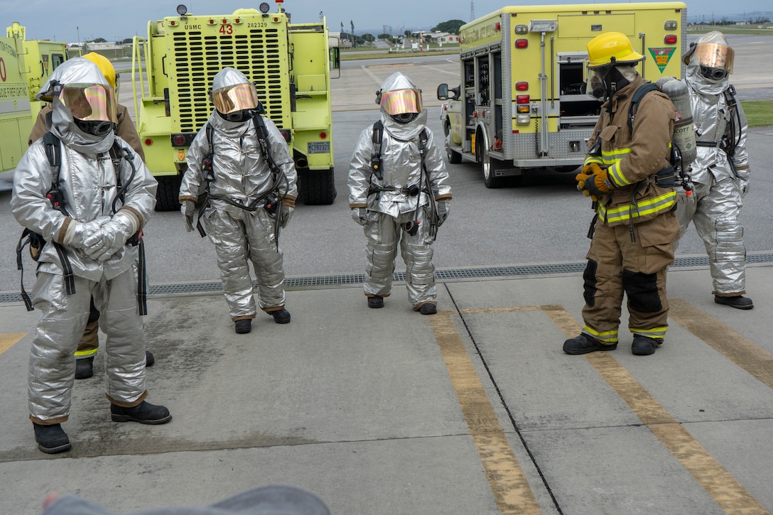 U.S. Marines with Marine Corp Air Station Futenma Crash, Fire and Rescue display their fire fighting suits Feb. 16 at the firehouse on MCAS Futenma. The Marines demonstrated how to put on their firefighting suits in under two minutes, simulating swift response time to real-life emergencies.. (U.S. Marine Corps photo by Pfc. Brennan Beauton)