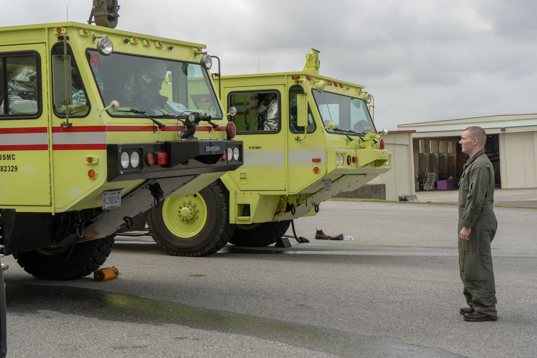 A U.S. Marine with Marine Corps Air Station Futenma Crash, Fire and Rescue observes his fellow Marines gear up Feb. 16 at the Firehouse on MCAS Futenma. The Marines demonstrated their swift reaction time to real-life emergencies by donning all their gear, and boarding their emergency response vehicles in less than two minutes. (U.S. Marine Corps photo by Pfc. Brennan Beauton)