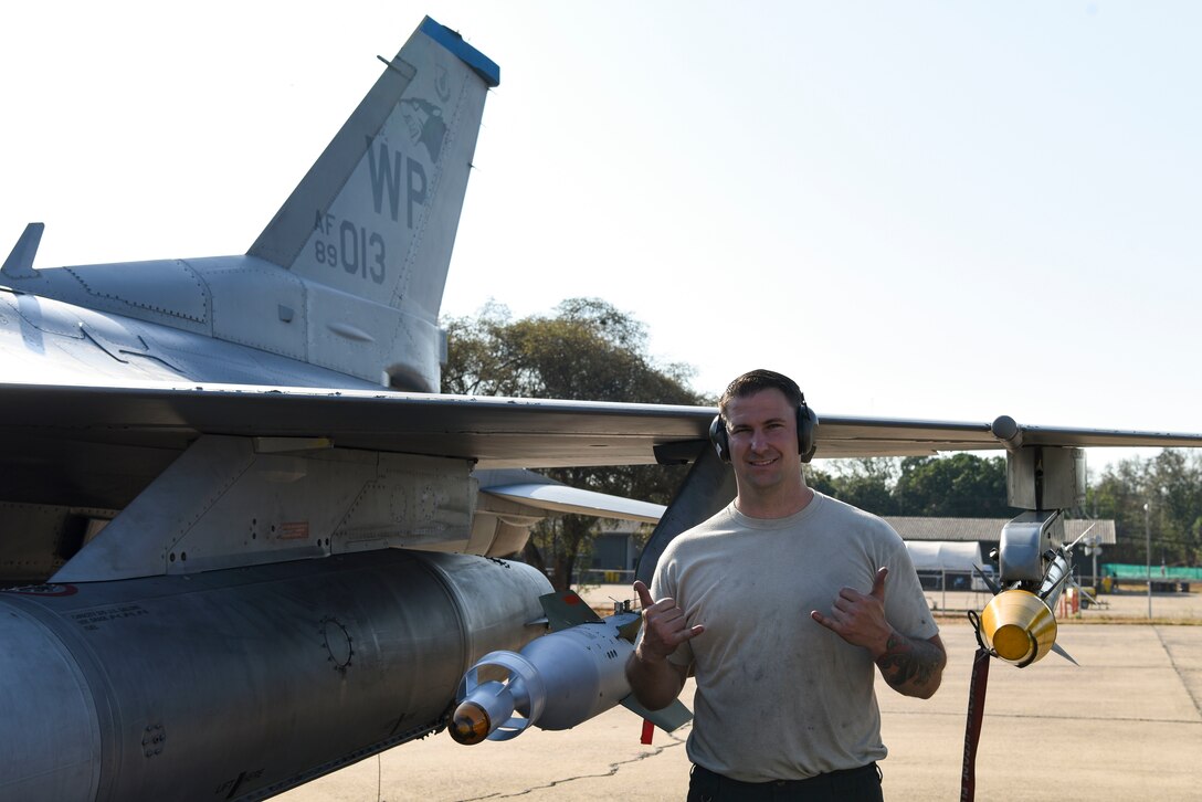 U.S. Air Force Staff Sgt. Travis Davis, 8th Aircraft Maintenance Squadron crew chief, gives the 35th Fighter Squadron's "Push It Up!" sign during Exercise Cobra Gold 2019 at Korat Royal Thai Air Force Base, Thailand, Feb. 19, 2019. Cobra Gold participants conduct multinational force, combined task force events that are vital to maintaining the readiness and interoperability of security forces across the region. (U.S. Air Force photo by Senior Airman Savannah L. Waters)