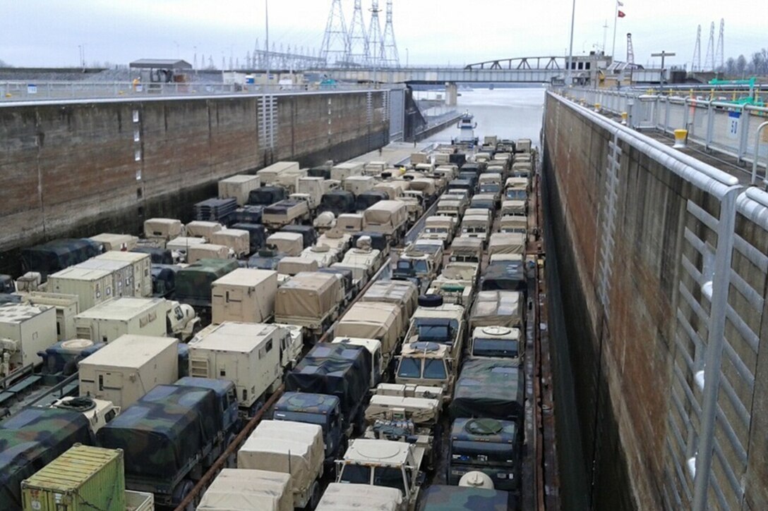 Army equipment is loaded on a barge.