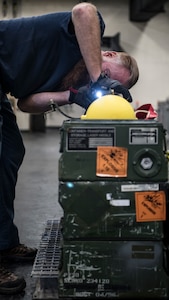 Greg Groover, Naval Air Systems Command munitions inspector, examines an AGM-114 HELLFIRE missile from a storage container Feb. 5, 2019, at the Naval Weapons Station in Goose Creek, S.C.